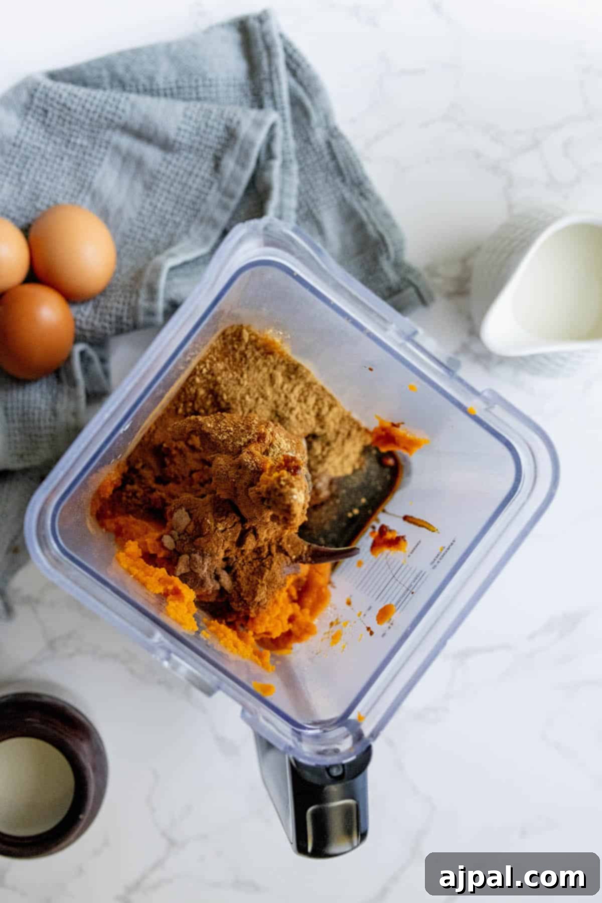 All the liquid ingredients for a pumpkin pie, including sweet potato puree and eggs, ready to be blended for the filling.