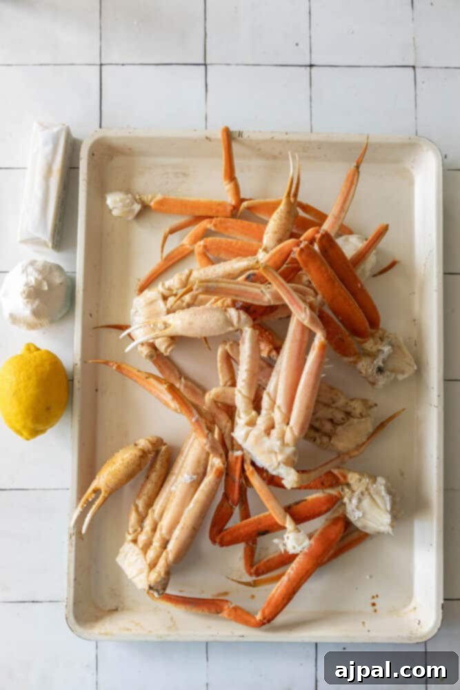 Baked snow crab legs on a white tray with lemon wedges.