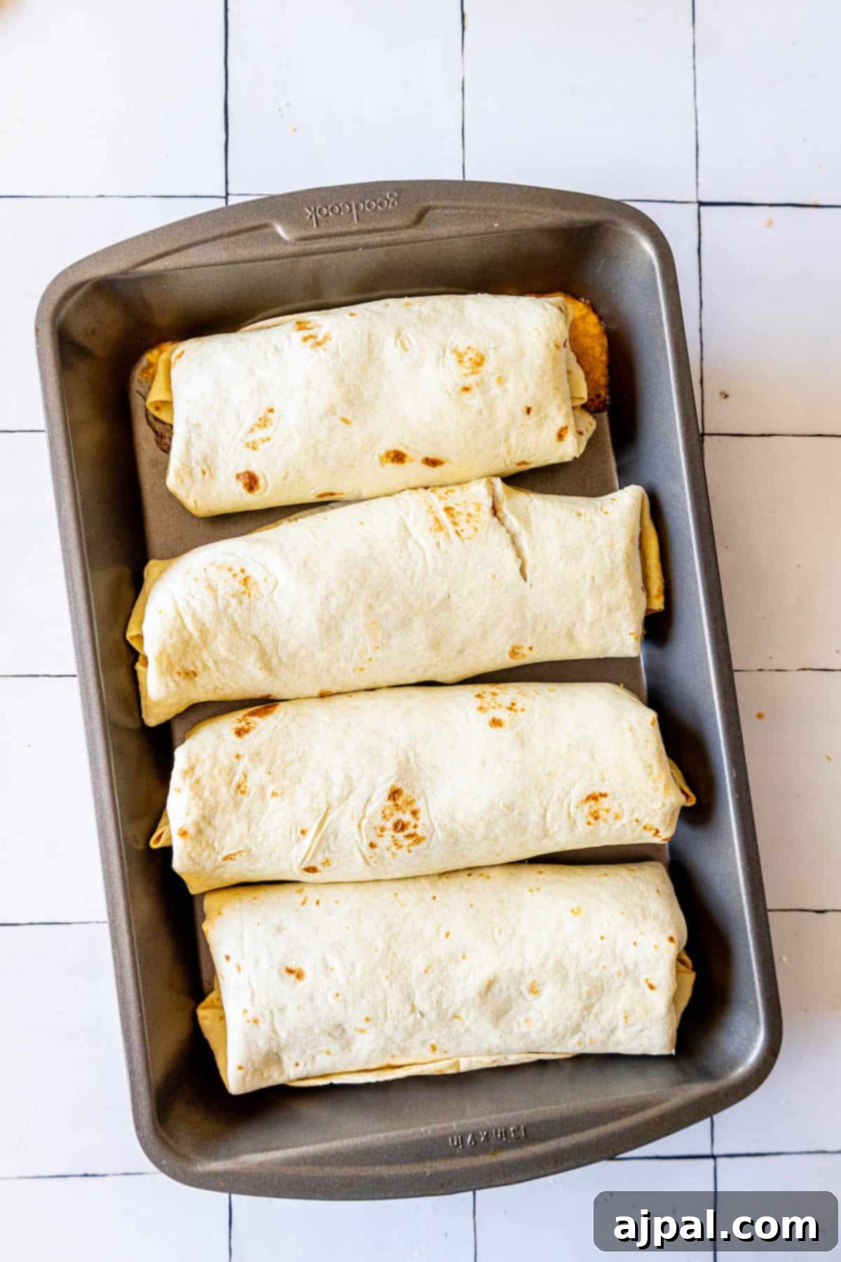 Oven-Baked Chicken Chimichangas 16 Four baked chimichangas artfully arranged on a rustic tiled surface.