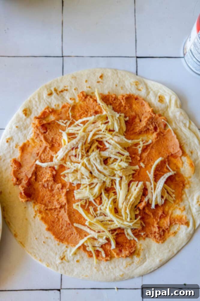 Oven-Baked Chicken Chimichangas 7 Spreading refried beans on a tortilla.