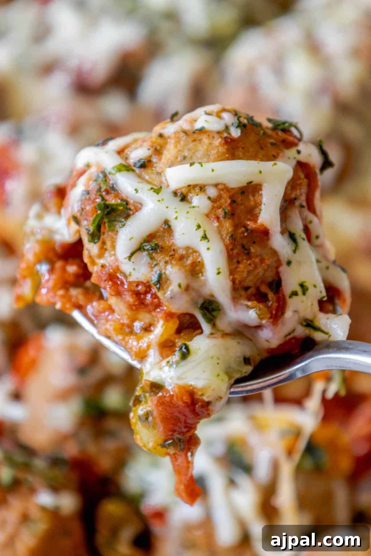 Italian Meatball Skillet Melt 2 A cheesy spoon is holding a piece of Italian pizza.