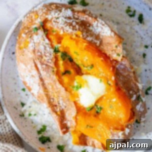 A salt-baked sweet potato with butter and parsley on a plate.