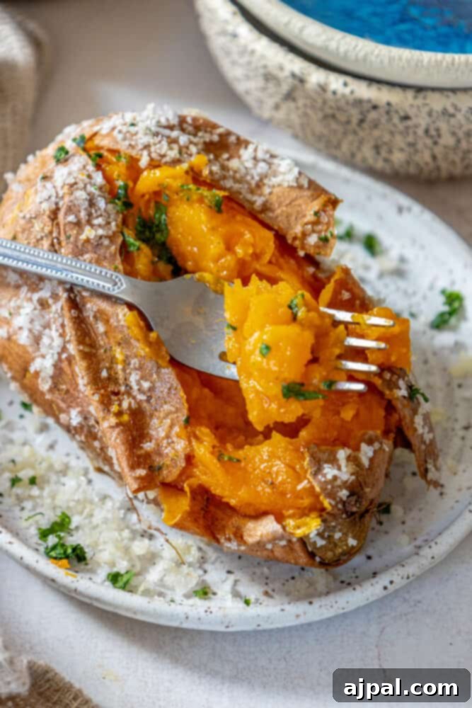 Perfectly Salt Baked Sweet Potatoes 3 A rustic plate showcases a perfectly salt-baked sweet potato, revealing its tender, orange flesh next to a fork, ready for tasting.