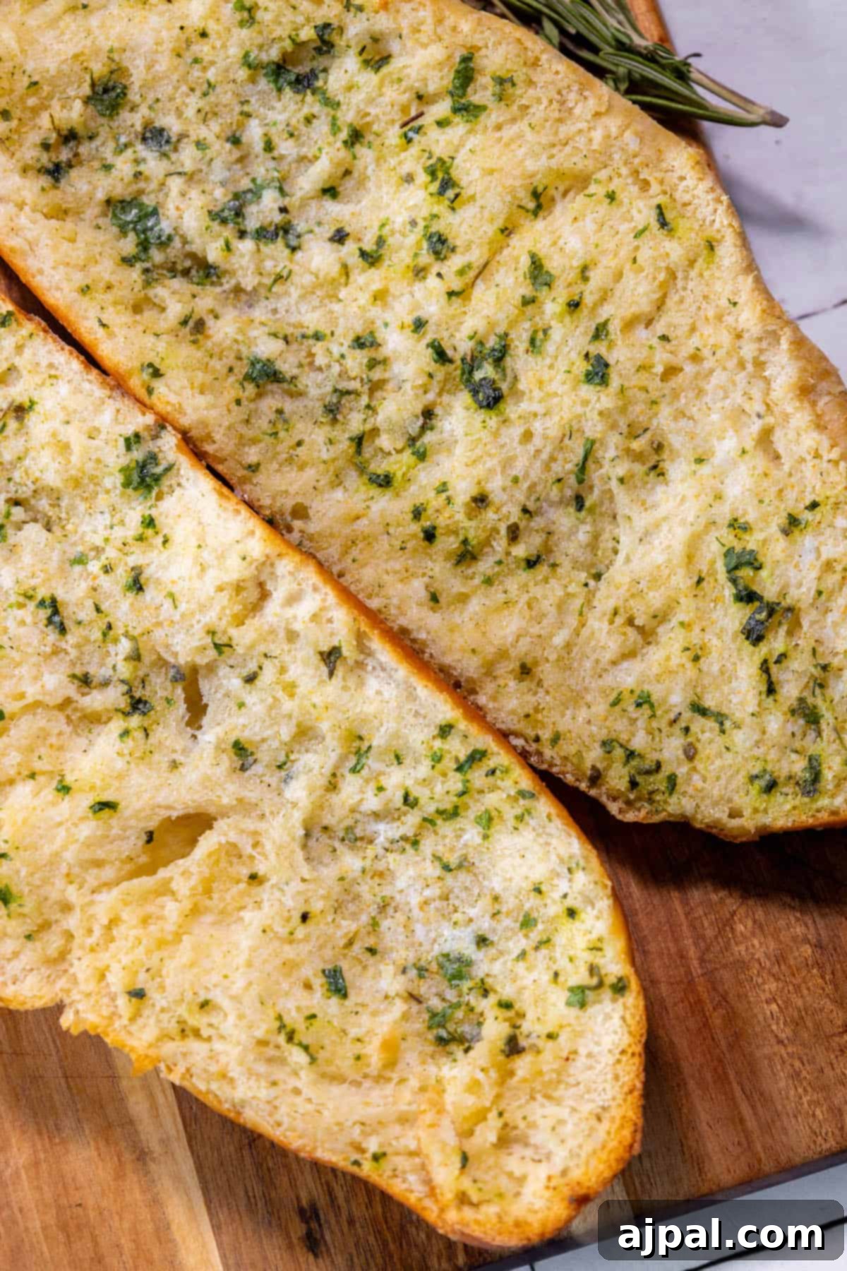Easy garlic bread made with two slices of bread and herbs on a cutting board.