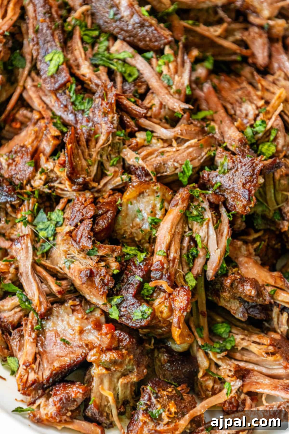 A plate showcasing a Perfect Chuck Roast on a white plate, garnished with fresh herbs.