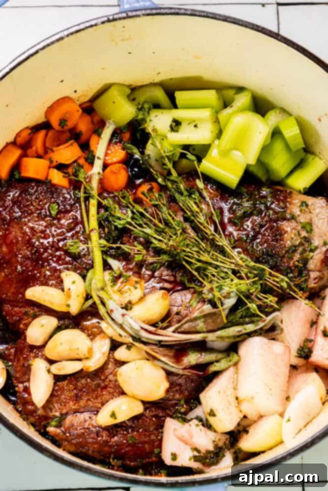 A pot filled with Perfect Chuck Roast and rich braising liquid, fresh from the oven.