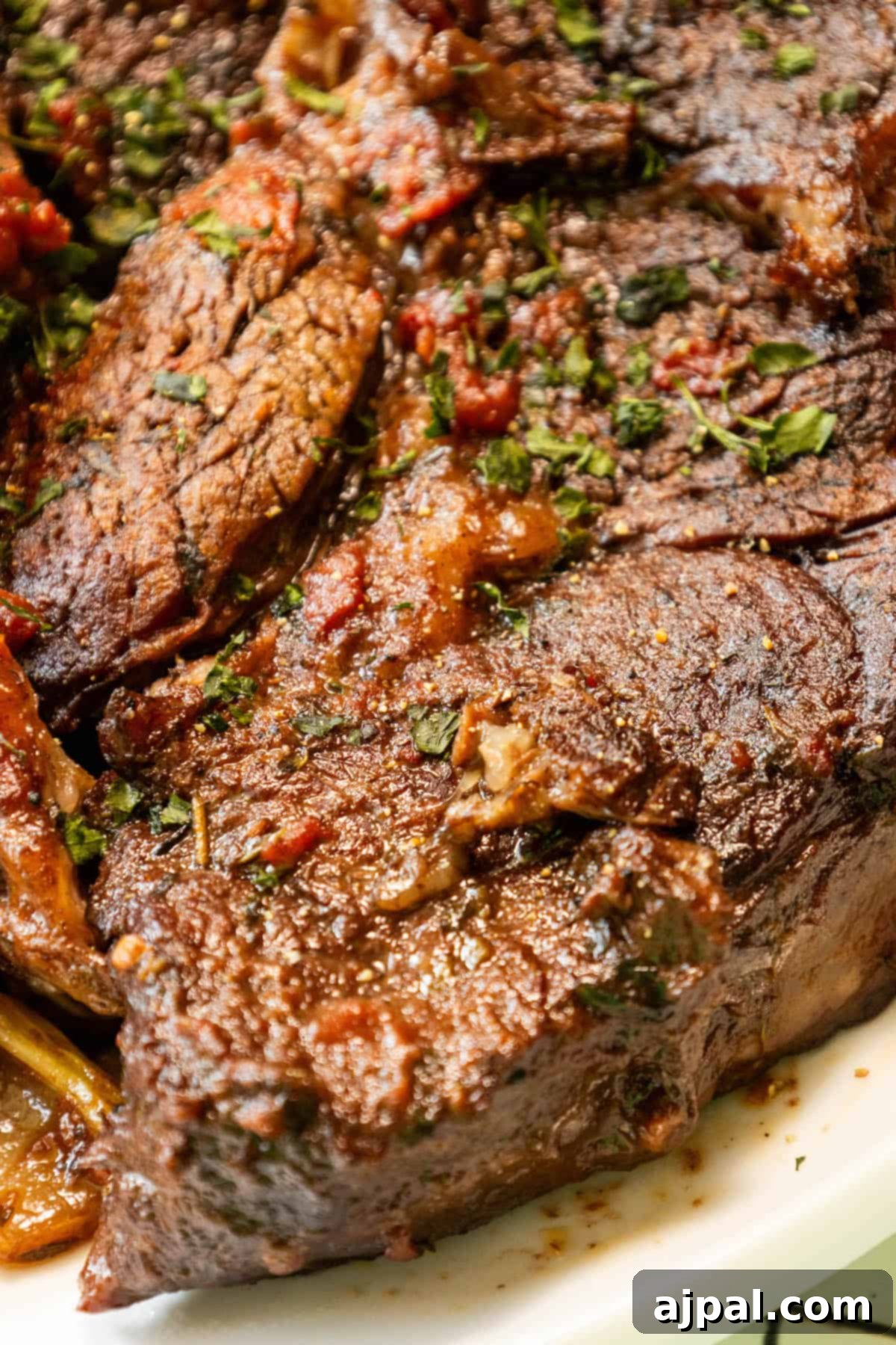 A perfect chuck roast with rich sauce and fresh herbs, presented elegantly.
