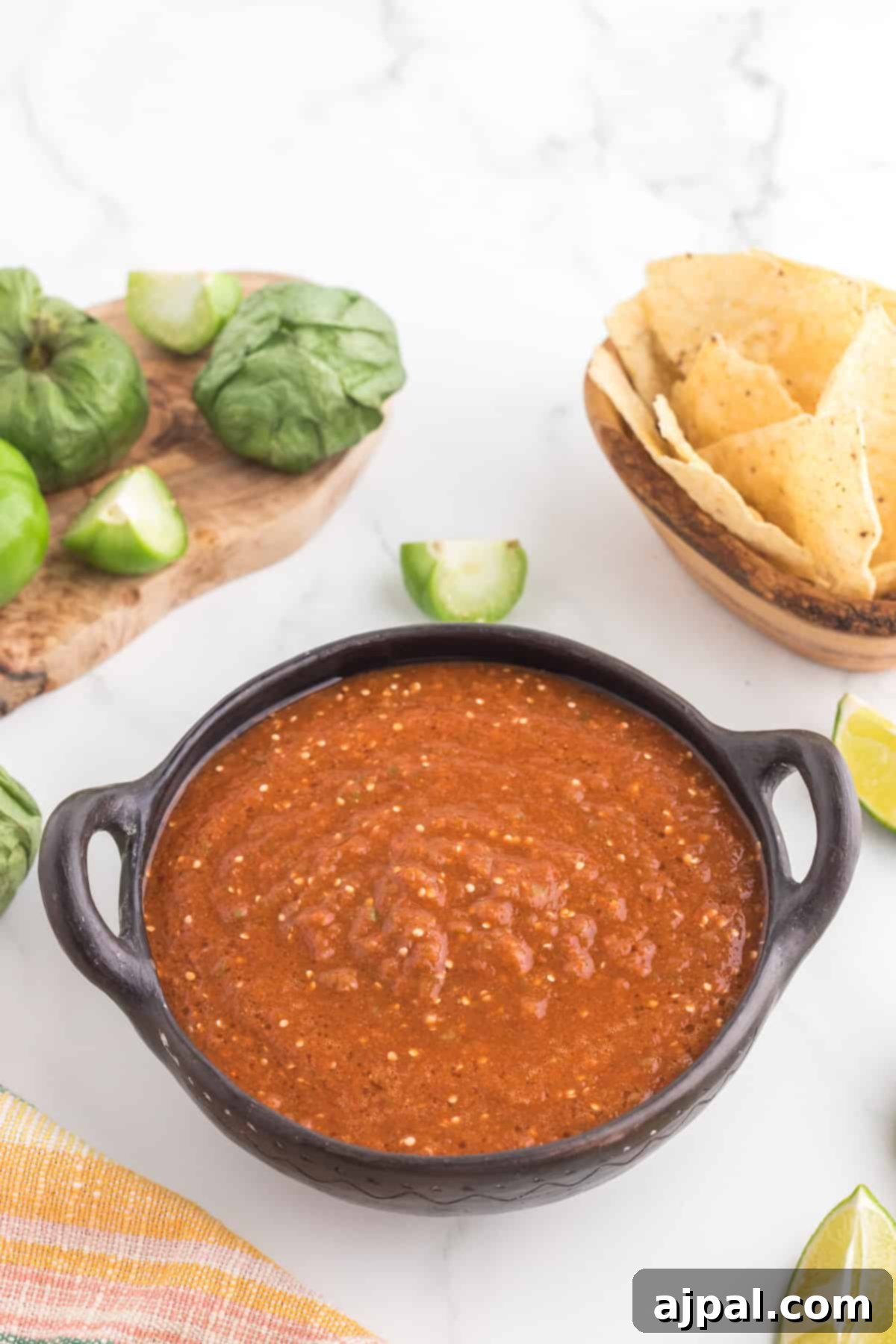 Smoky Chipotle Blaze 3 A rustic wooden table displays a vibrant bowl of Copycat Chipotle Red Salsa, surrounded by crisp tortilla chips and fresh lime wedges, ready for dipping.