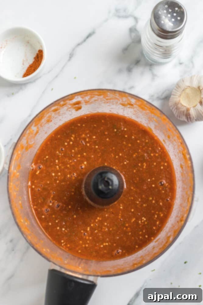 Smoky Chipotle Blaze 9 A food processor, filled with vibrant green salsa, perfectly captures the chunky texture of the freshly blended Chipotle Hot Salsa.