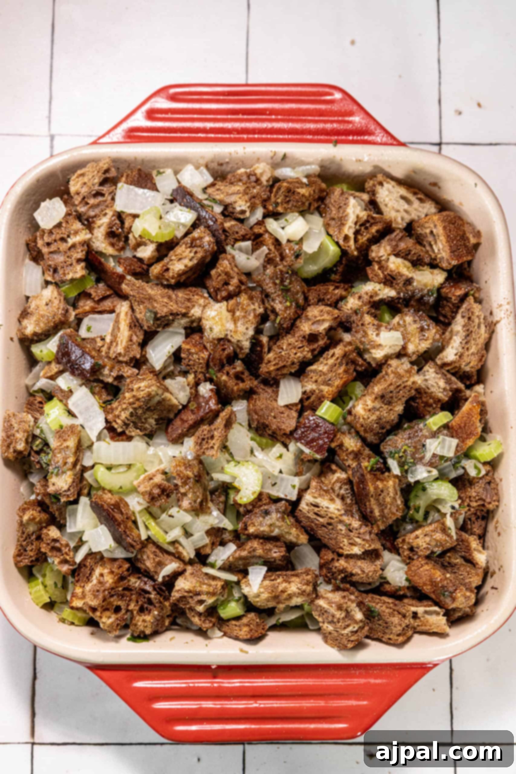 Hearty Bacon Rye Stuffing 7 A red baking dish filled with bacon and vegetables.