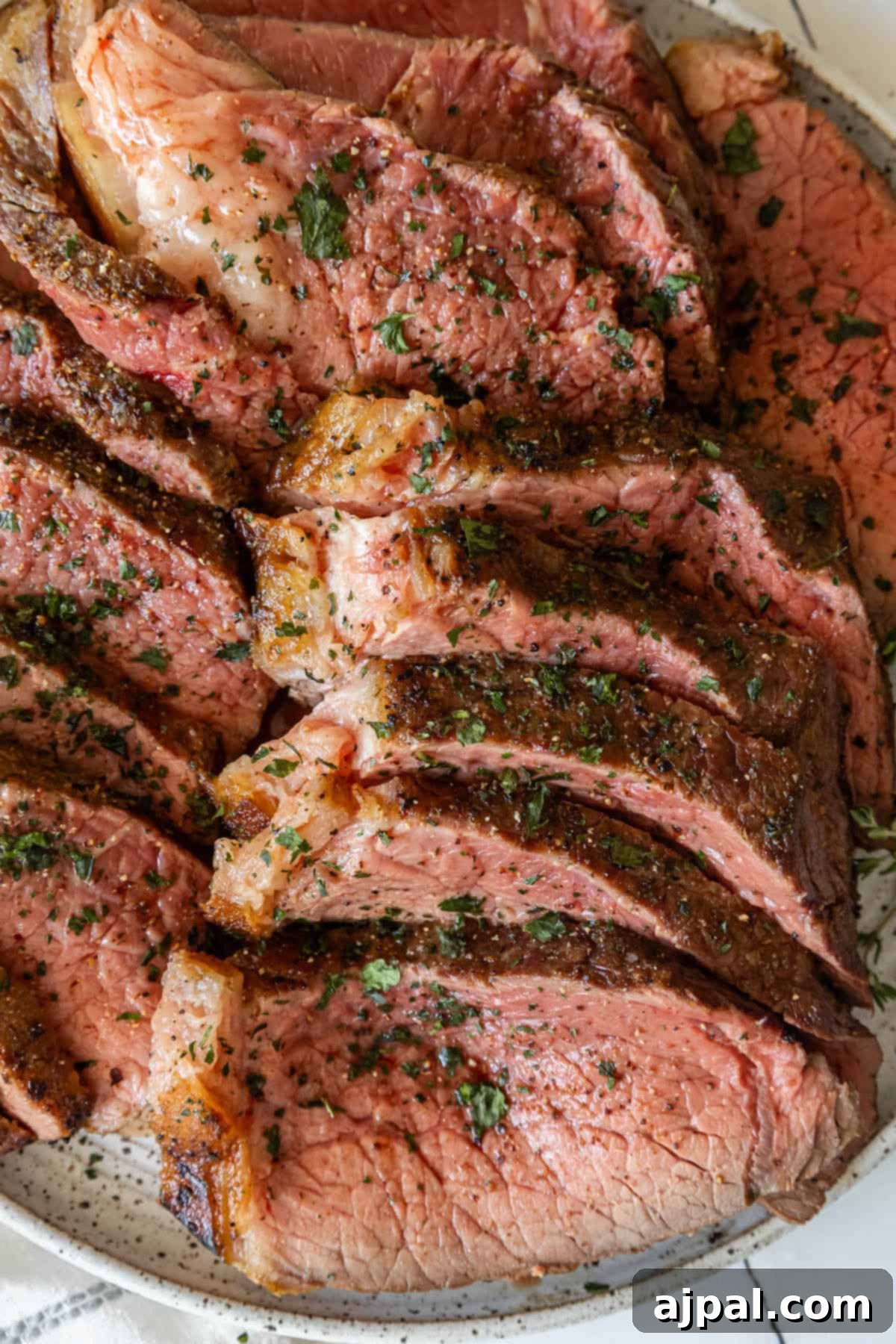 Steak on a plate with herb butter, garnished with fresh herbs.
