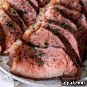 Beef tenderloin on a white plate with herb butter.
