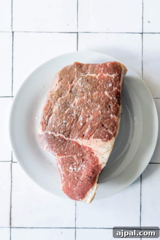 A succulent Bottom Round Roast, perfectly cooked to perfection, served on a pristine white plate.