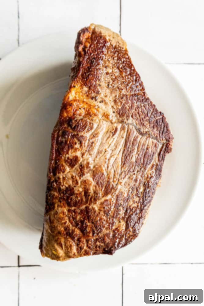 Bottom Round Roast with herb butter served on a white plate.