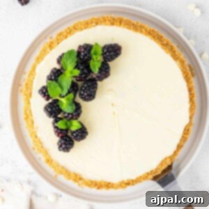 A slice of white chocolate blackberry tart with mint on a white plate, ready to serve.