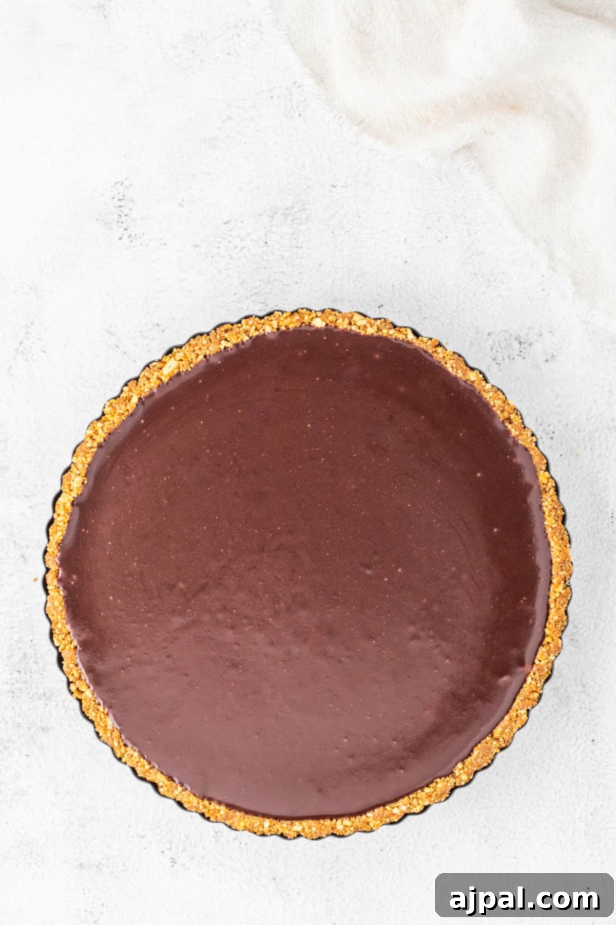 A finished gingerbread chocolate tart resting elegantly on a pristine white surface, ready to be sliced and enjoyed.