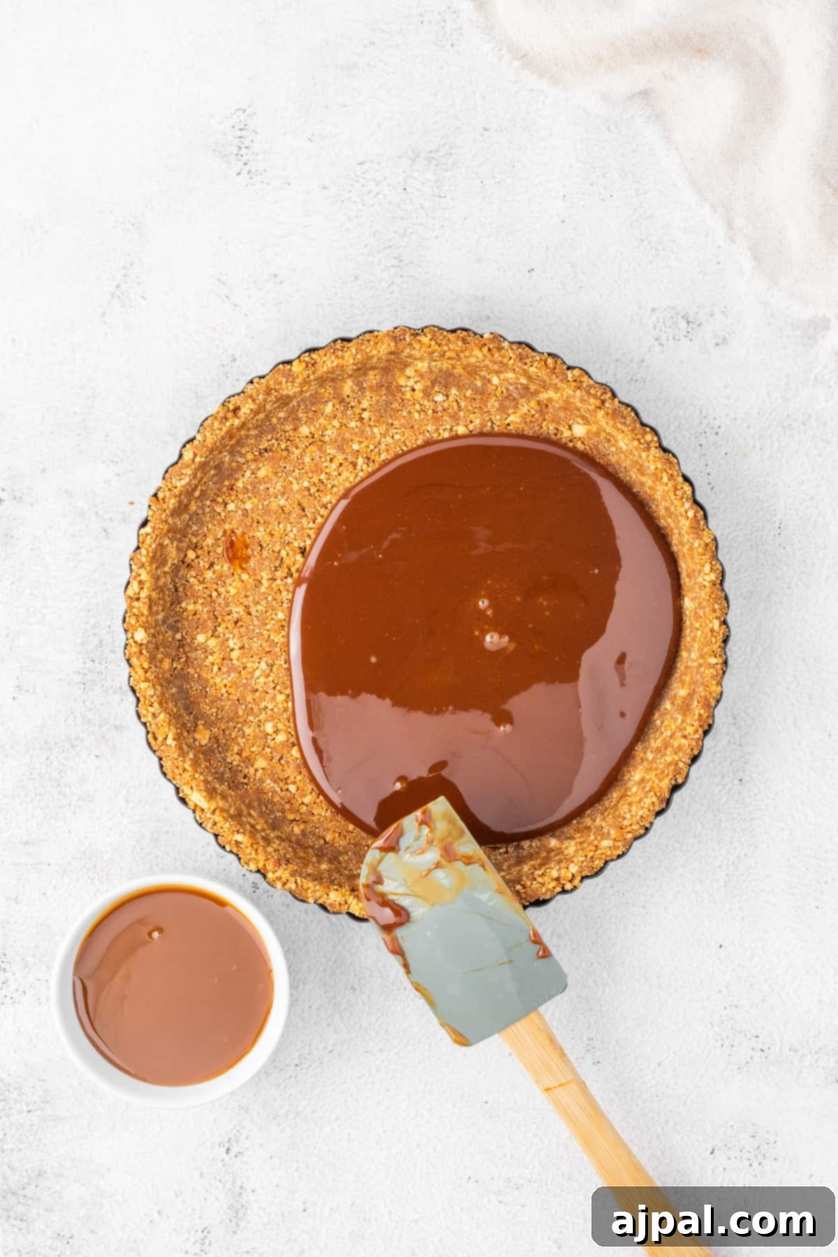 A delightful gingerbread chocolate tart drizzled with rich caramel sauce, accompanied by a handy spoon for easy enjoyment.
