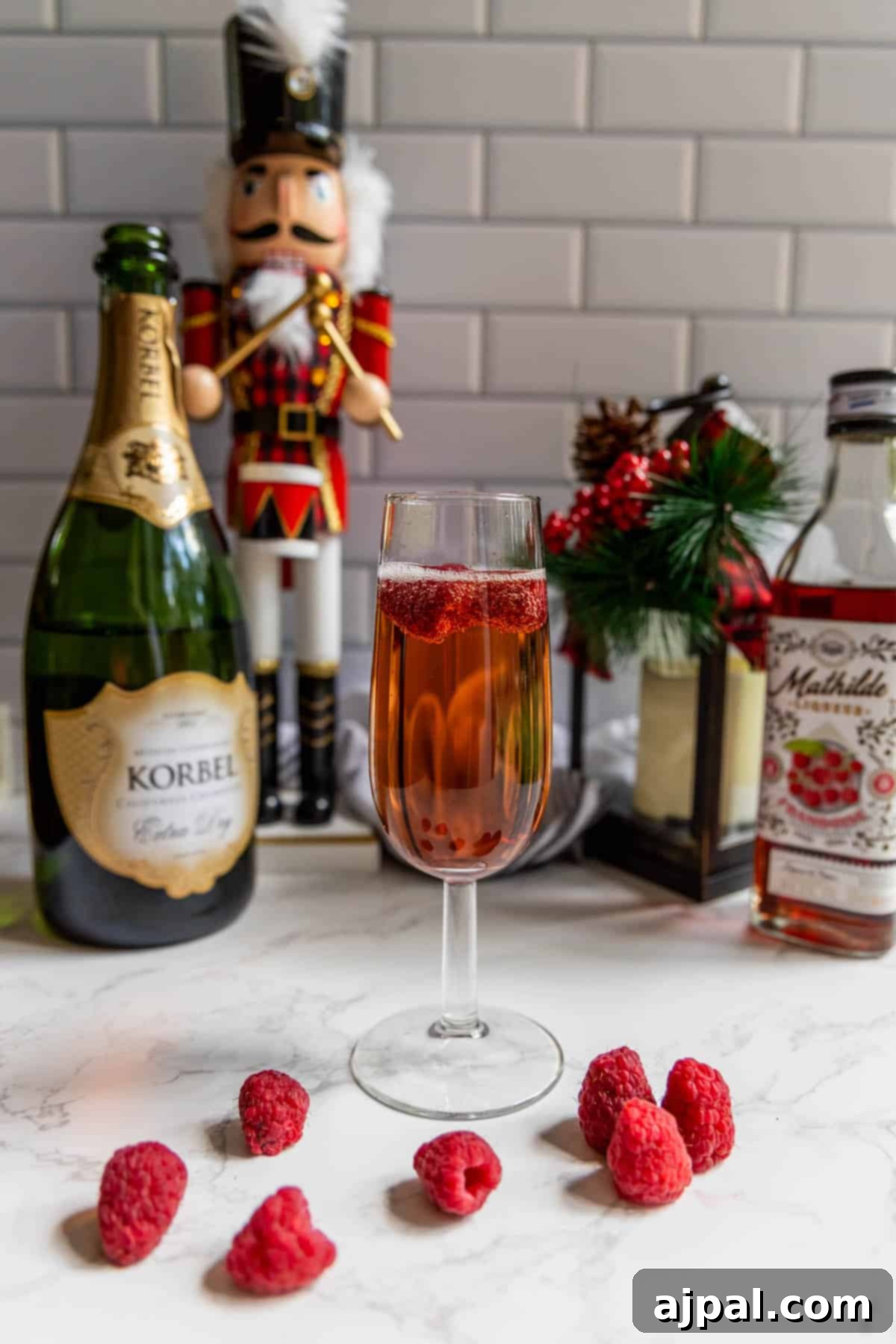 Raspberry Champagne Glow 3 A raspberry champagne sparkler elegantly garnished with fresh raspberries and served alongside a classic nutcracker, evoking a festive holiday mood.