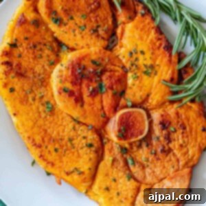Skillet ham steak served with roasted sweet potatoes and rosemary sprigs.
