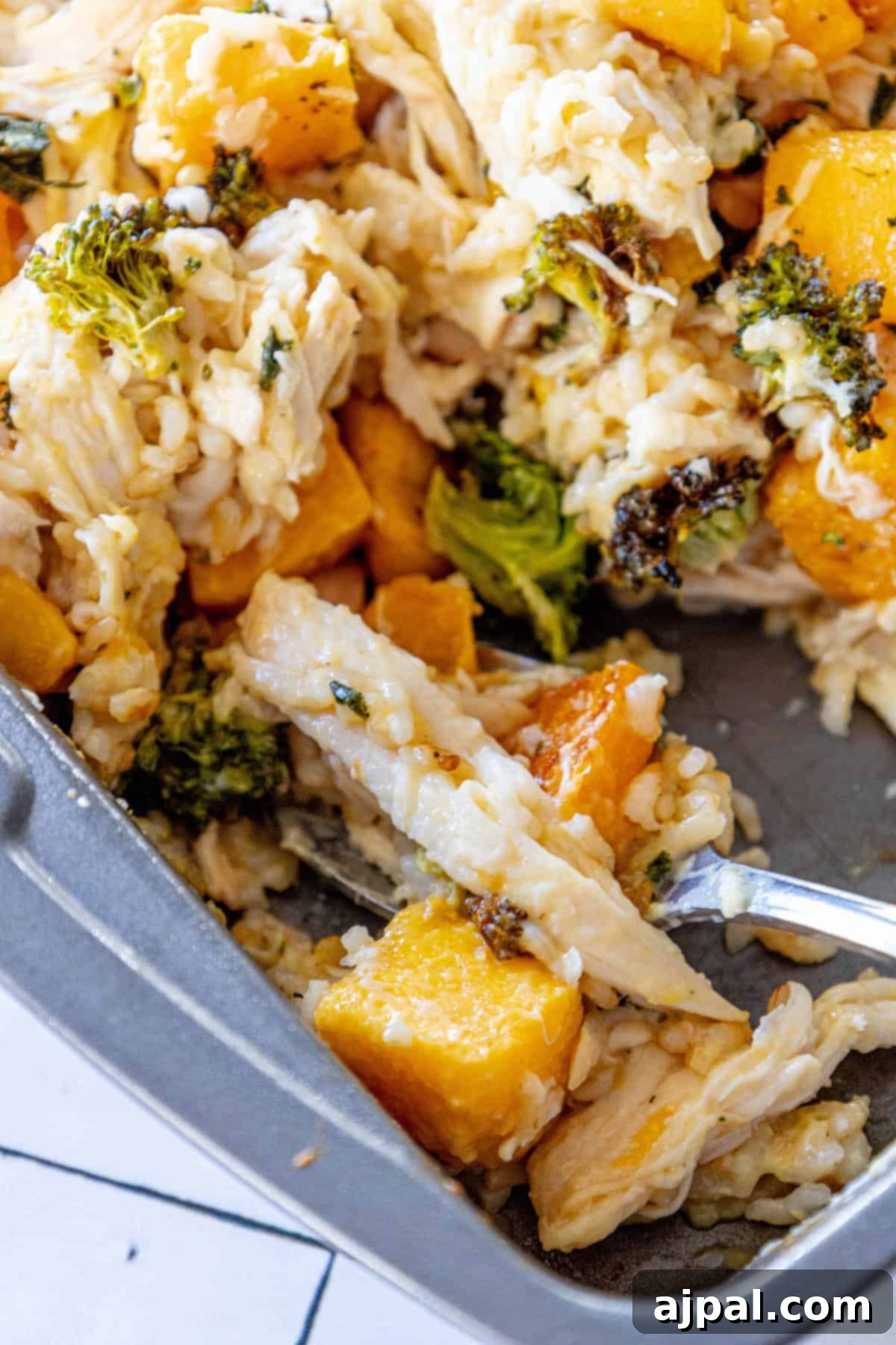 A bubbling casserole dish brimming with golden chicken, roasted butternut squash, and bright green broccoli florets.