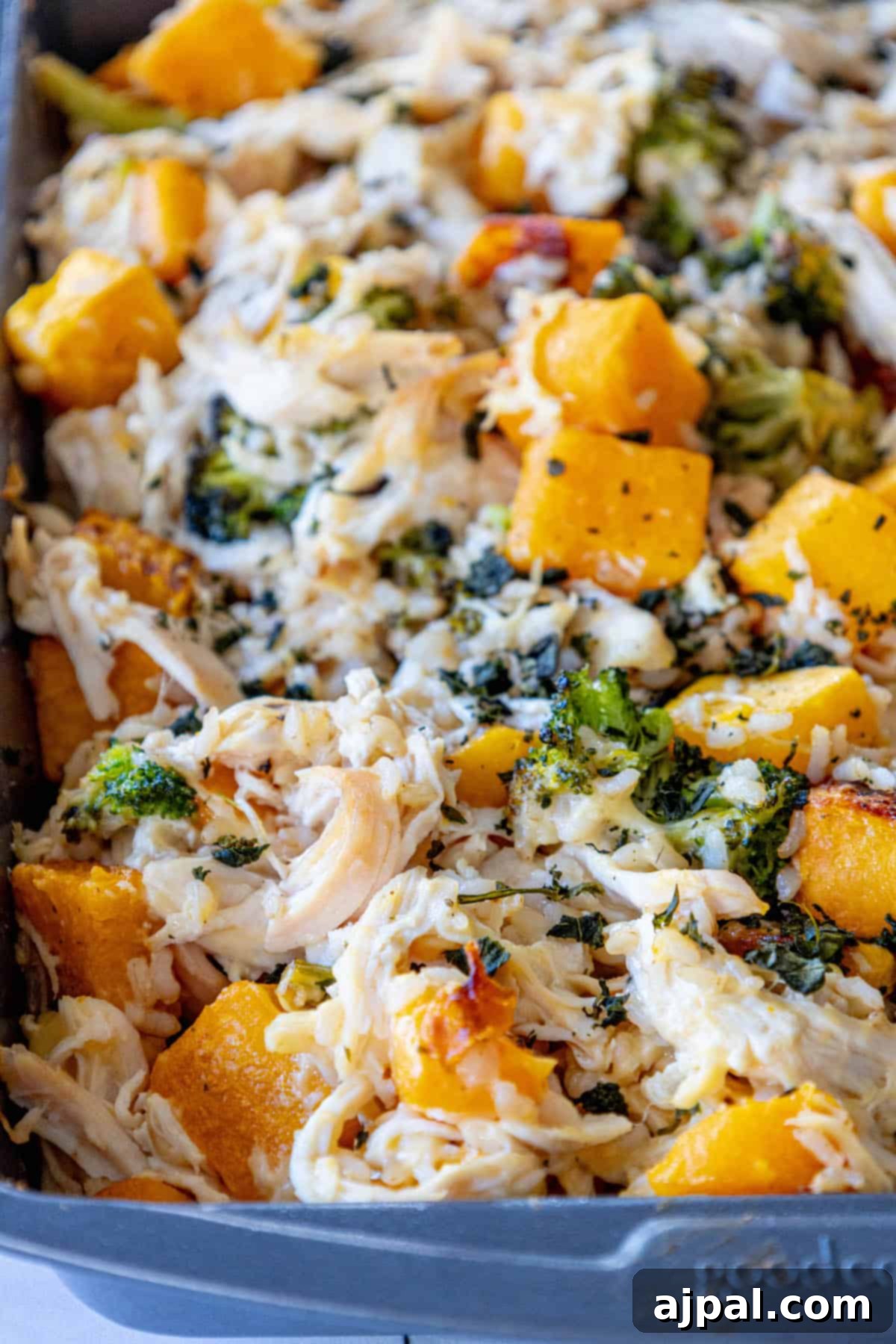 A casserole dish filled with golden chicken, butternut squash, and broccoli, ready to be enjoyed.