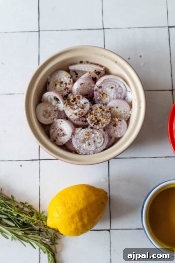 A delicious bowl of shallot confit, showcasing caramelized shallots and glistening lemon zest, garnished with fresh herbs on a charming tiled backdrop.