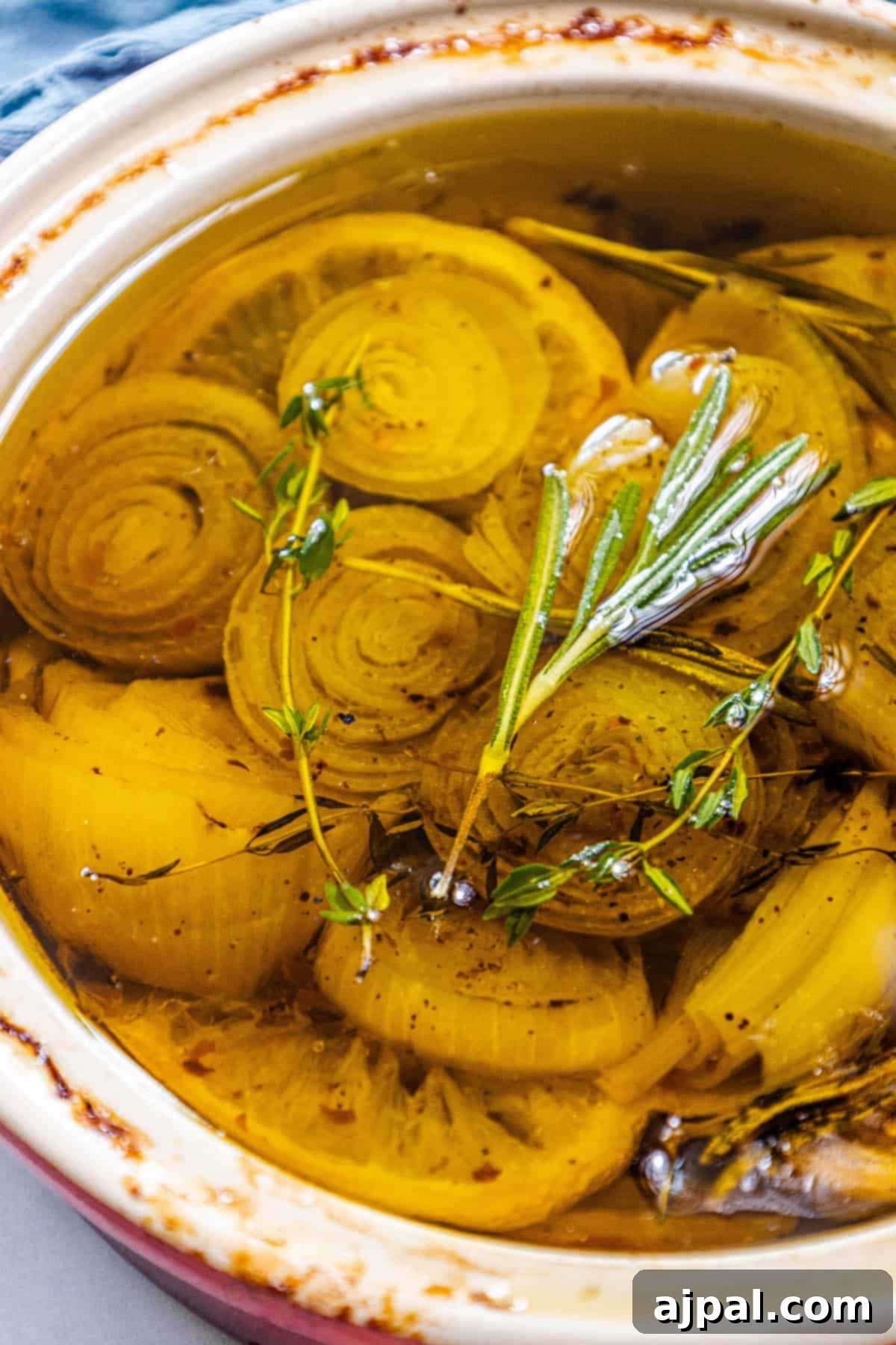 A bowl brimming with glistening, shallot-infused confit, elegantly garnished with fresh sprigs of thyme for an aromatic finish.