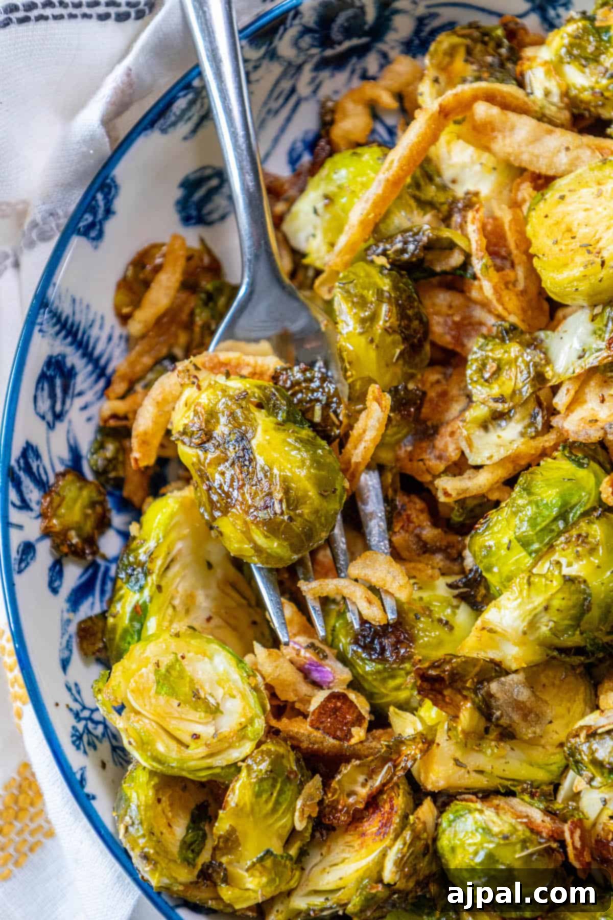Caramelized Brussels Sprouts and Sweet Onions 7 Roasted Brussels sprouts in a blue and white bowl with a fork.