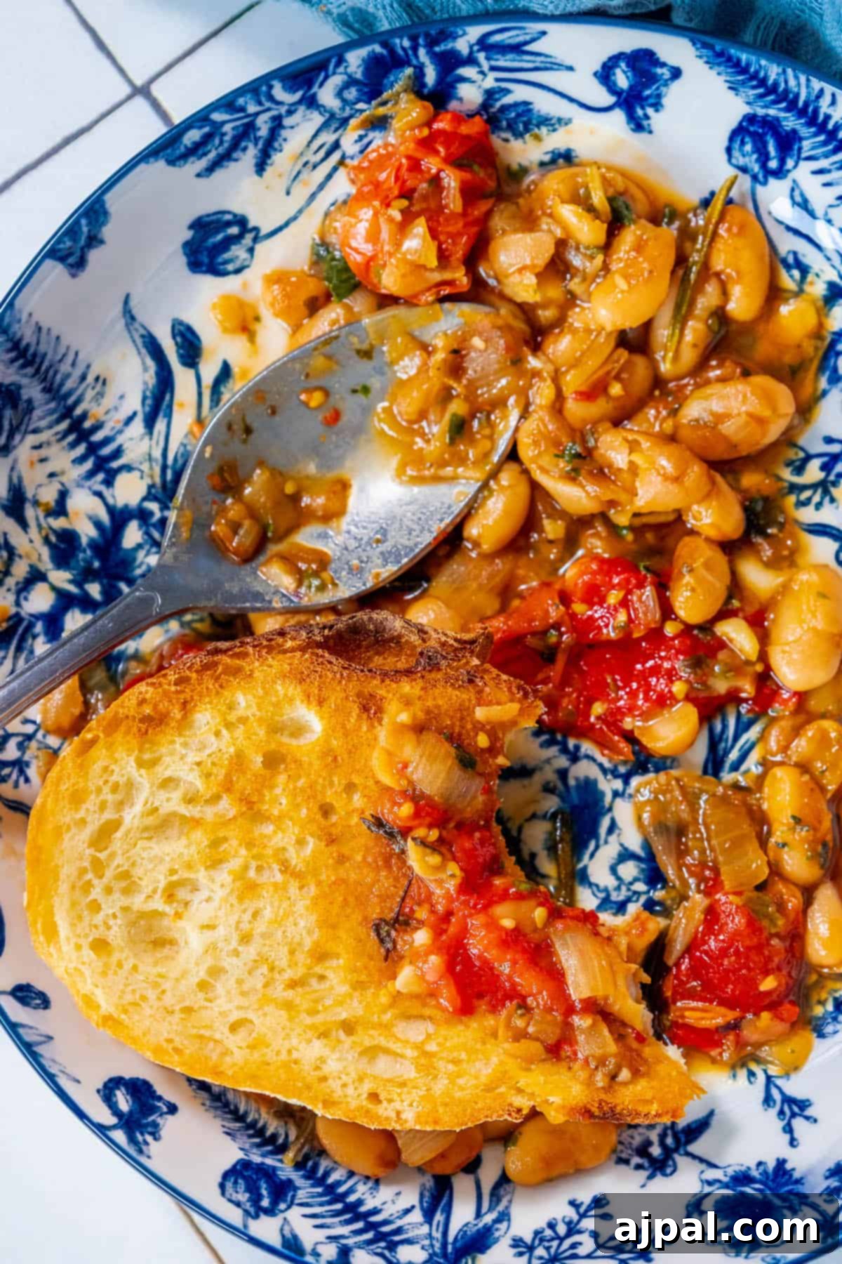 An inviting, SEO-optimized plate featuring perfectly cooked white beans with vibrant diced tomatoes, showcasing the rich texture and appealing presentation of the herbed brothy white beans.