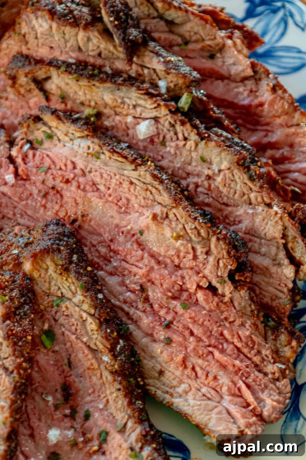 A reverse seared flank steak served on a blue and white plate.