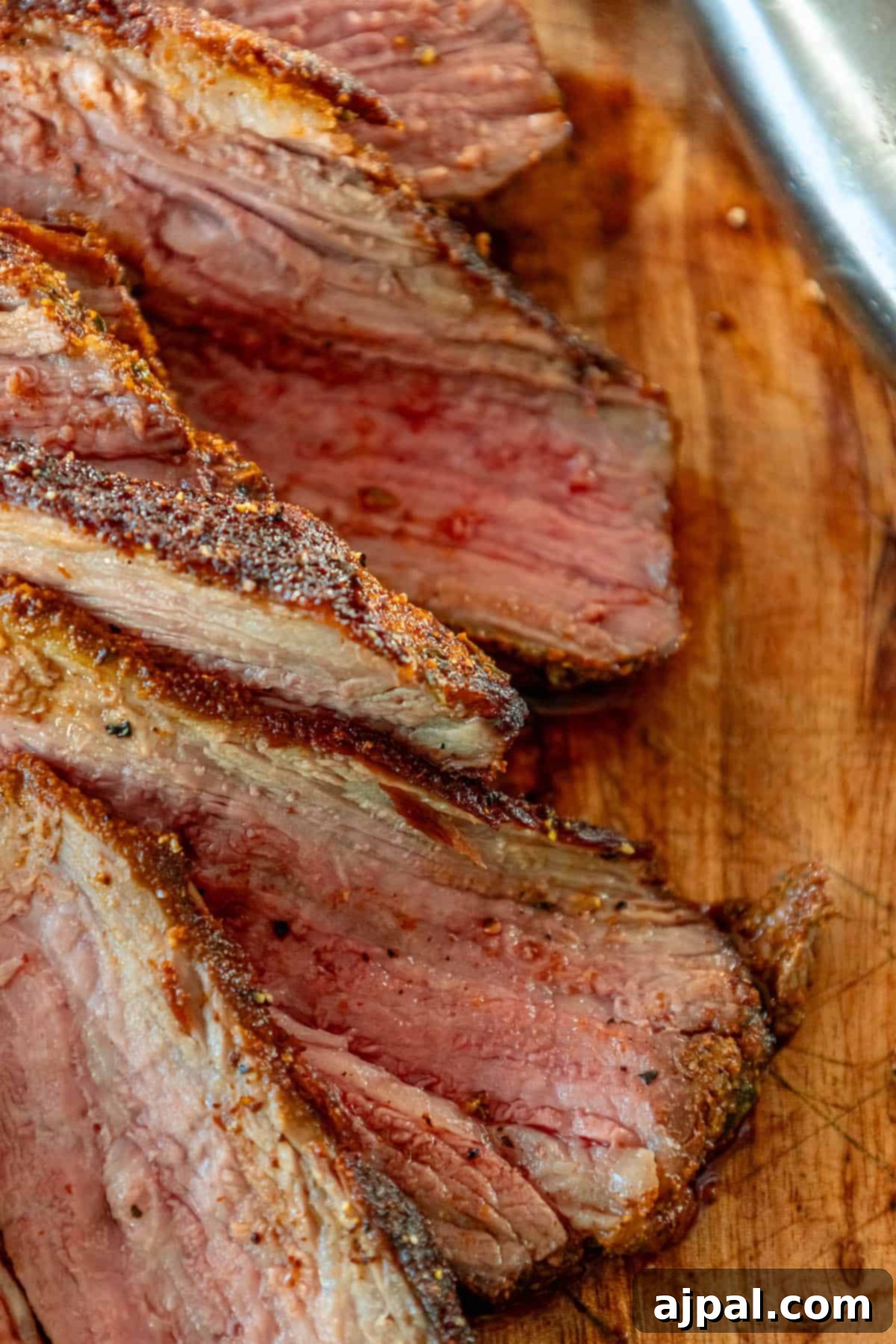 Reverse seared tri-tip steak slices on a cutting board with a knife.