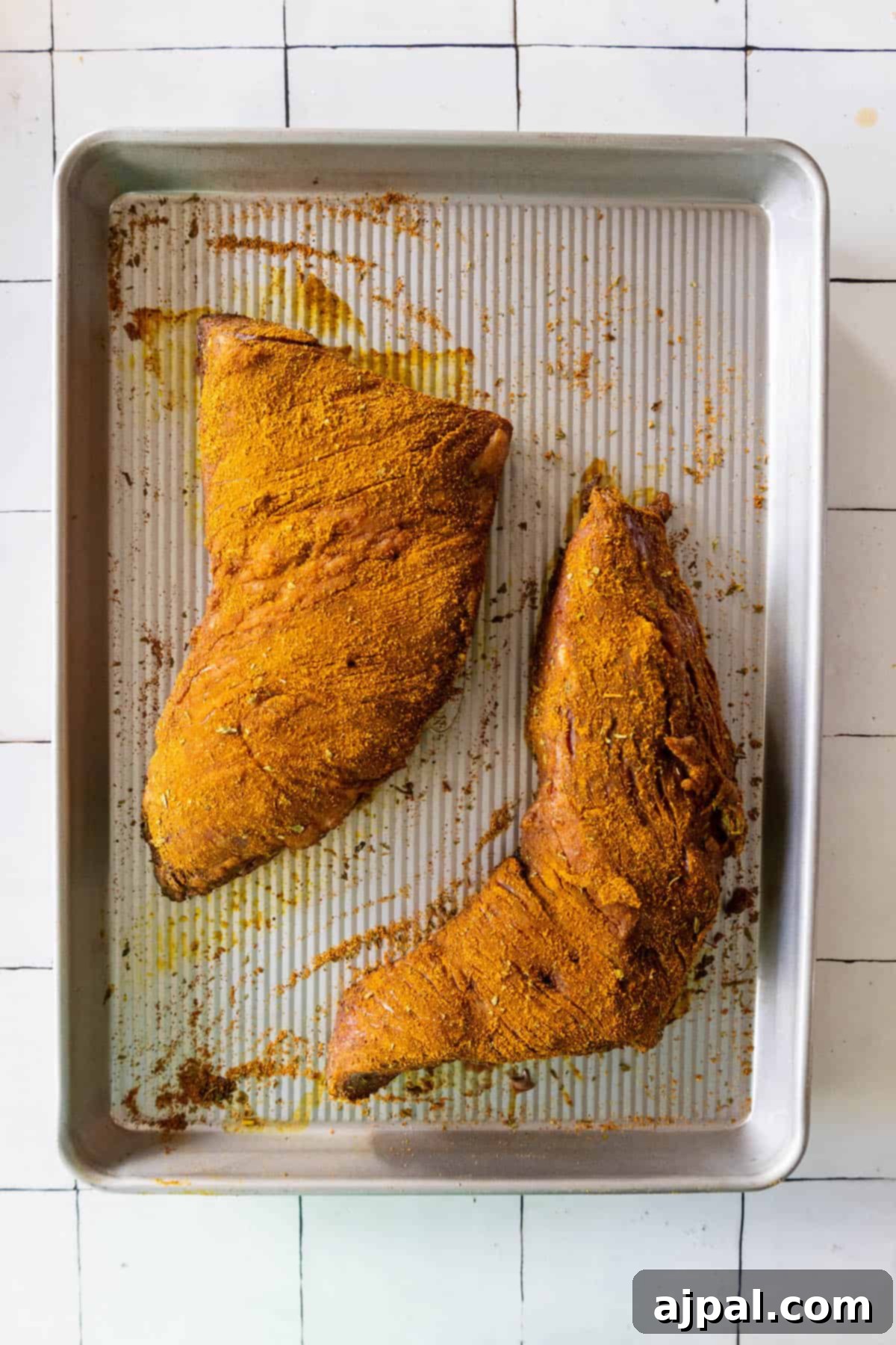 Two tri tip steaks on a baking sheet, ready for reverse searing.