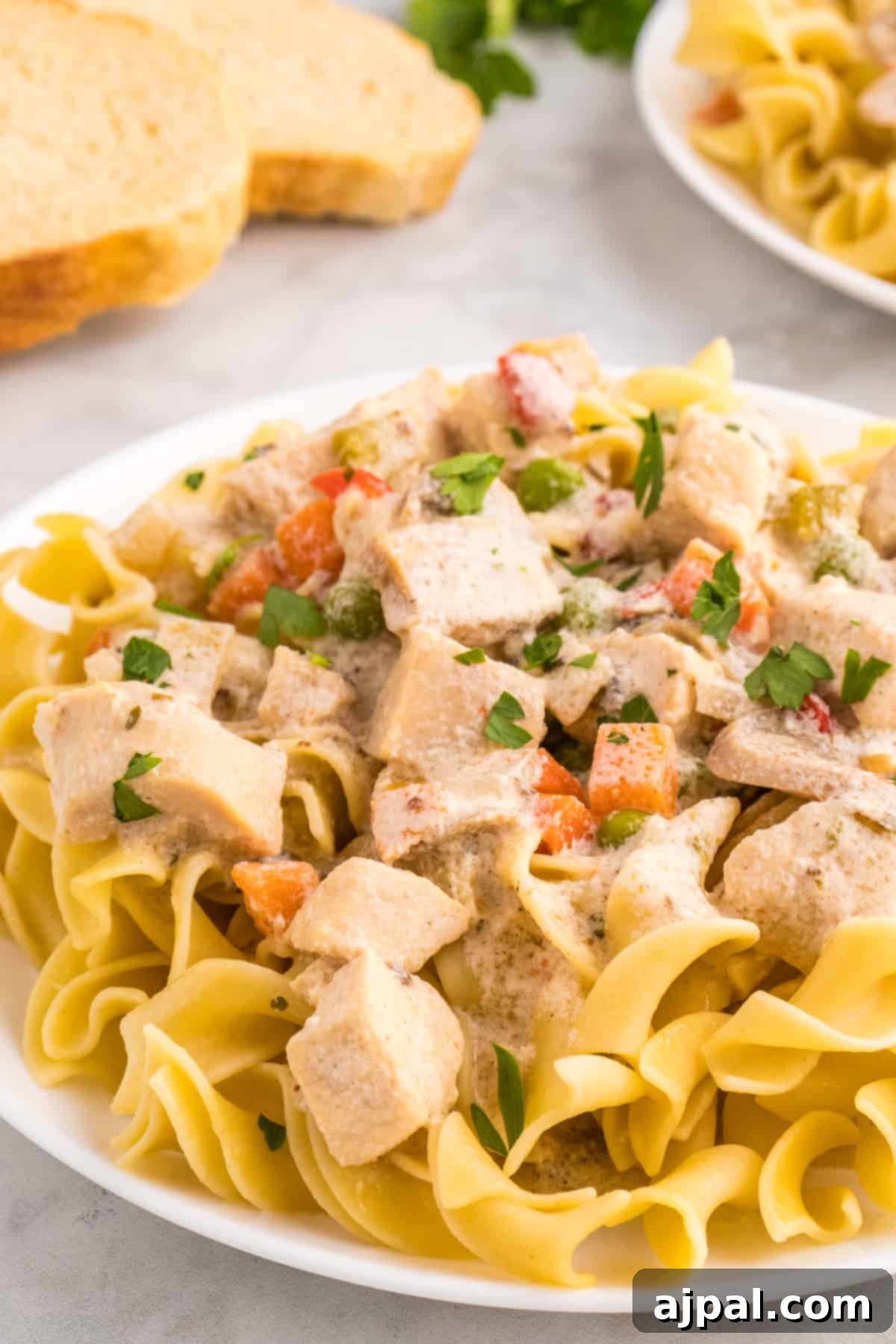 Easy Slow Cooker Chicken a la King 13 A slow cooker chicken a la king with vegetables served over a plate of pasta.