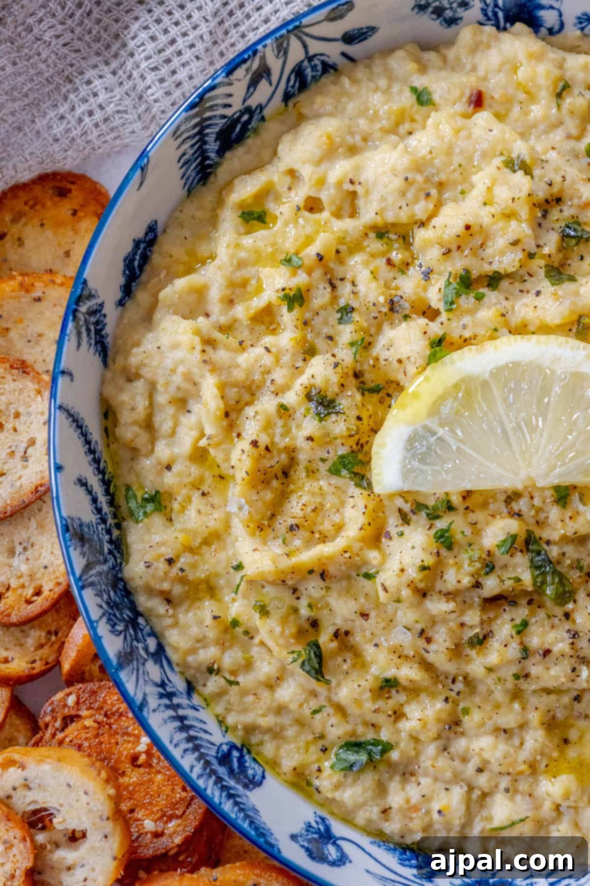 A bowl of chickpea hummus with a slice of lemon.
