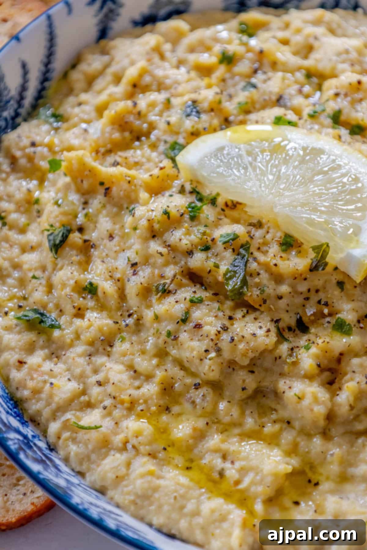 A bowl of hummus with a slice of lemon.