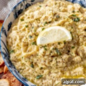 A bowl of hummus with a slice of lemon.