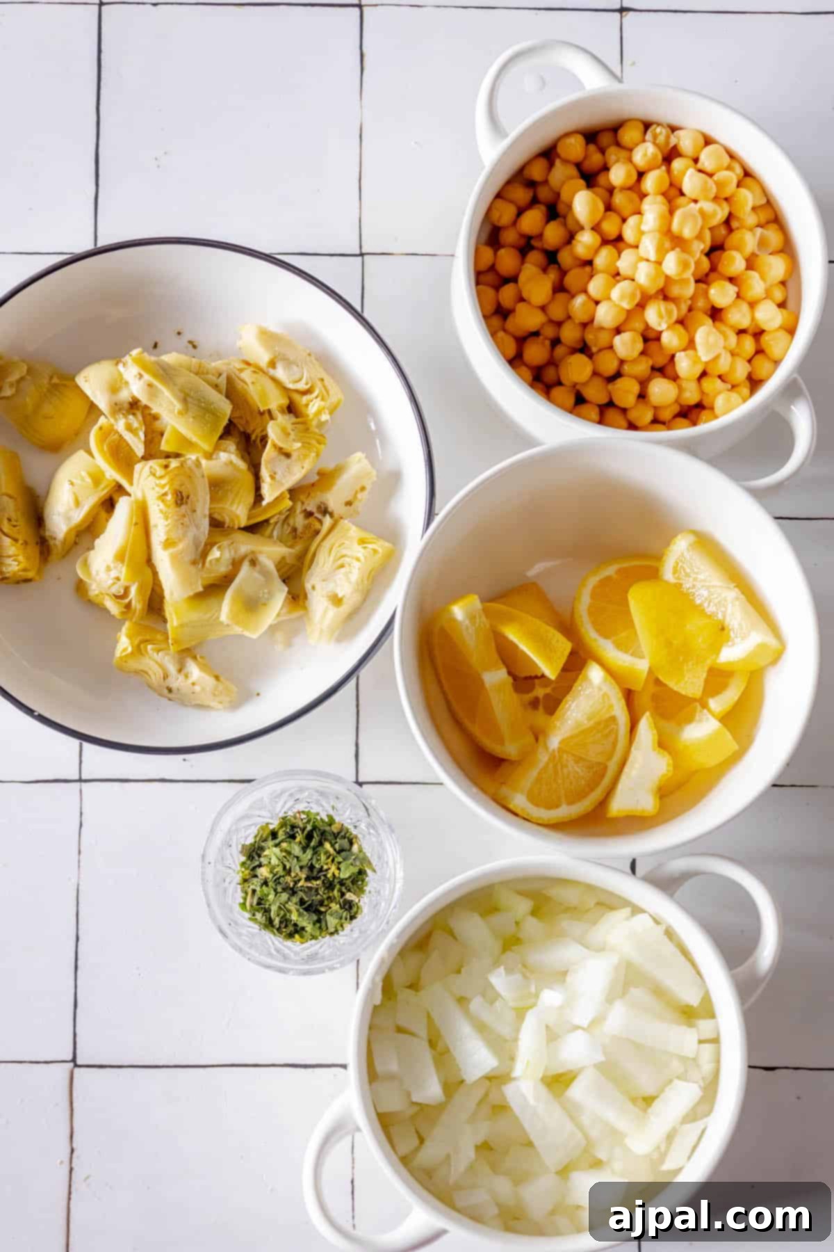 Four bowls of roasted food on a tiled floor.