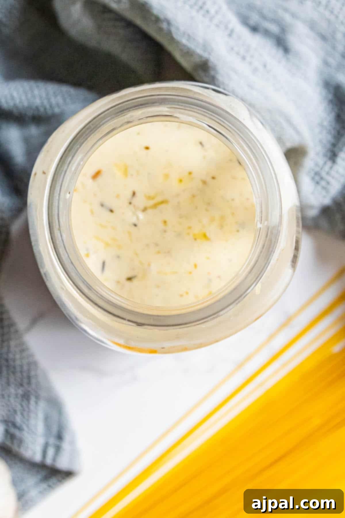 Indulgent Alfredo Perfection 3 A jar filled with homemade Alfredo sauce, sitting gracefully beside a tempting bowl of freshly cooked noodles, ready to be combined for a quick and satisfying meal.