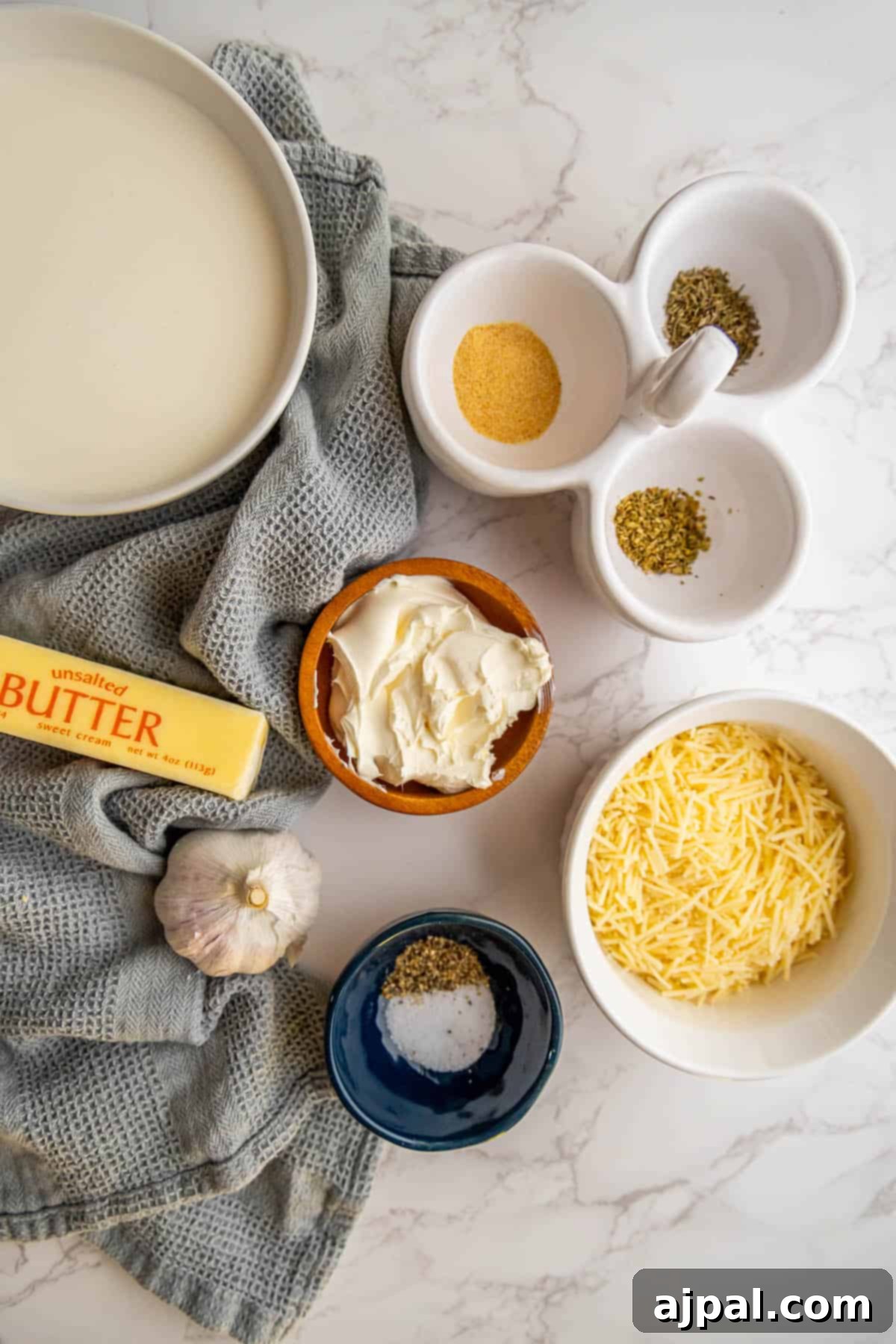 Perfect Homemade Alfredo Sauce 5 A thoughtfully arranged selection of ingredients essential for a creamy Alfredo sauce, including fresh herbs, butter, and various cheeses, laid out on a clean surface.