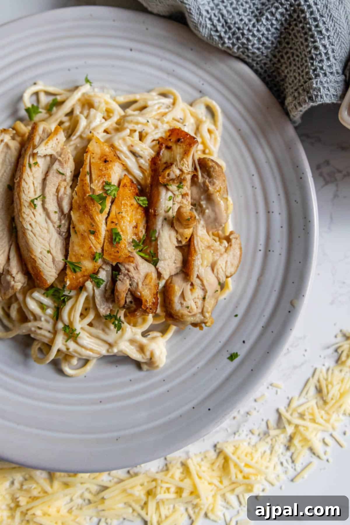 Creamy Chicken Alfredo Perfection 5 Chicken parmigiana on a white plate with parmesan cheese.