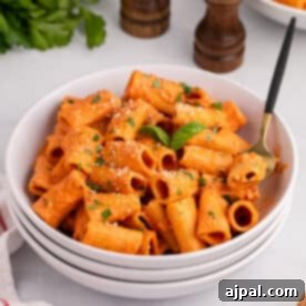 A dish of spicy rigatoni pasta with parmesan cheese and parsley.