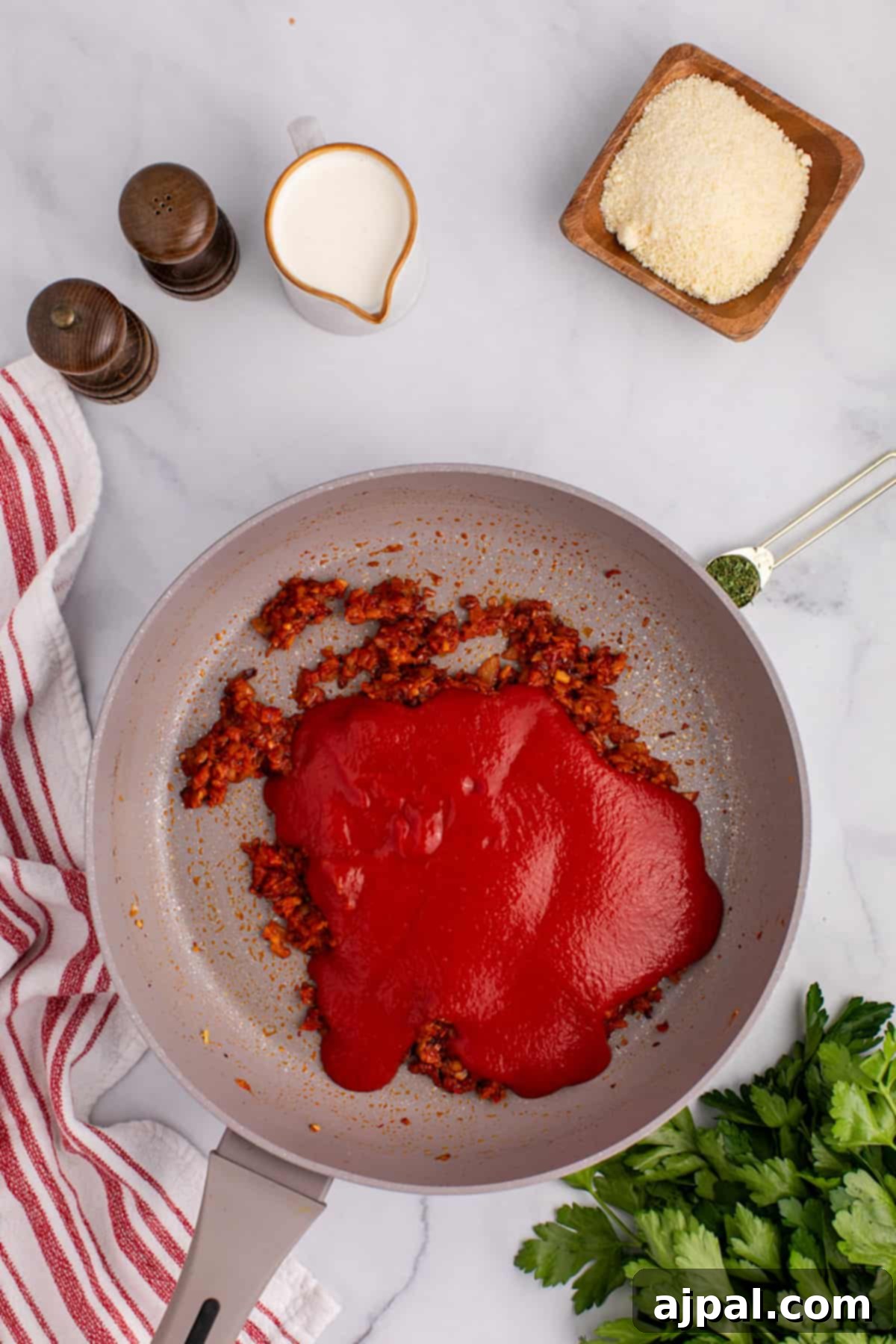 A spicy frying pan with red sauce and rigatoni pasta on it, just before mixing.