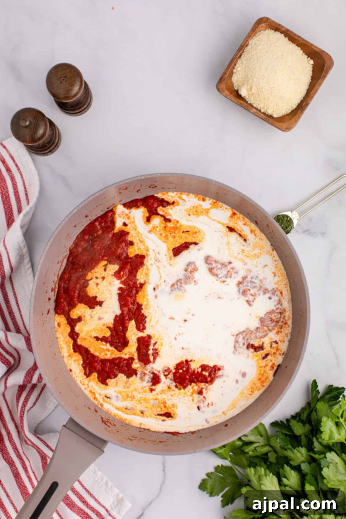 Rigatoni pasta tossed in a spicy sauce and sprinkled with parmesan cheese in a pan.