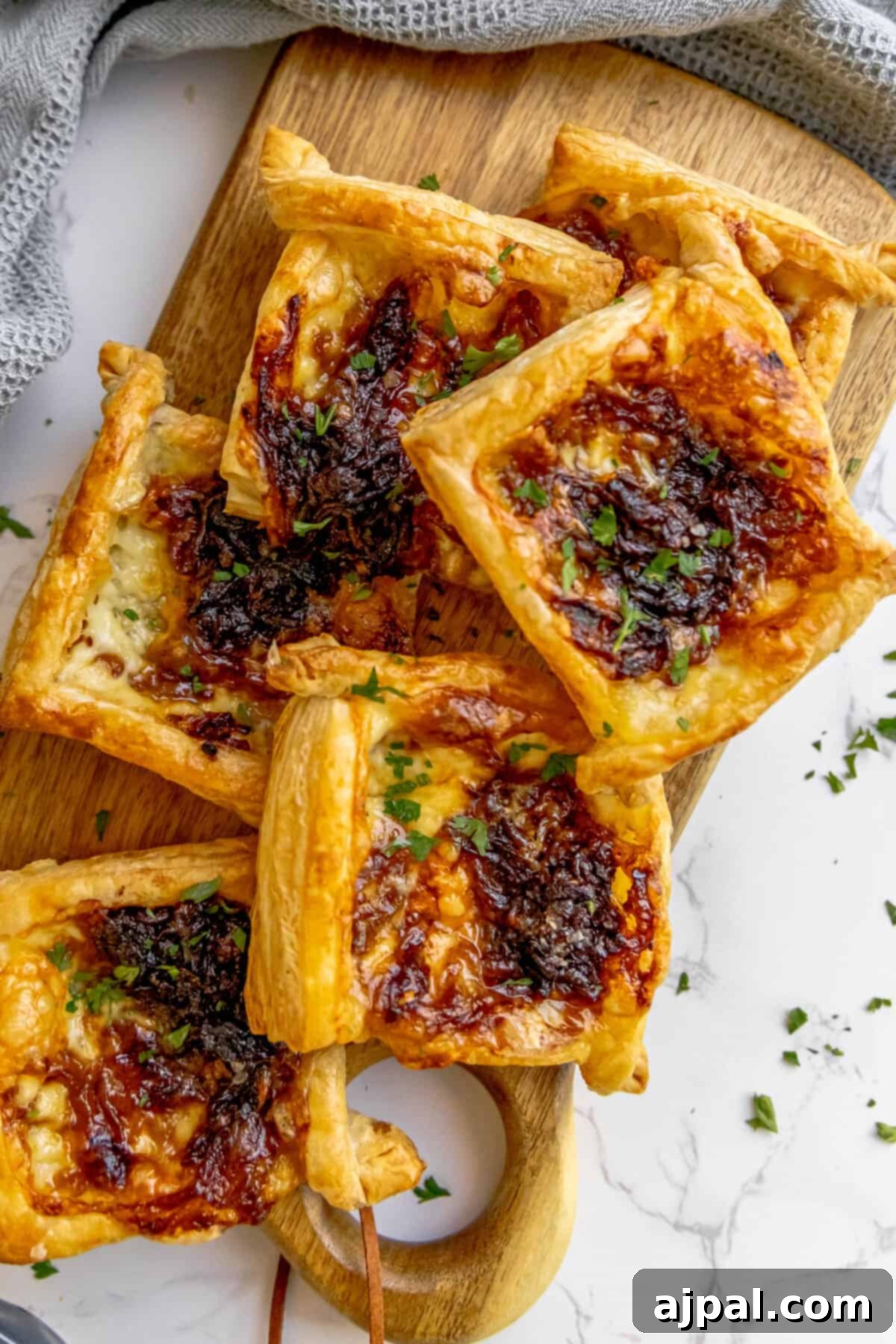 A wooden cutting board with elegant caramelized onion and brie tarts.