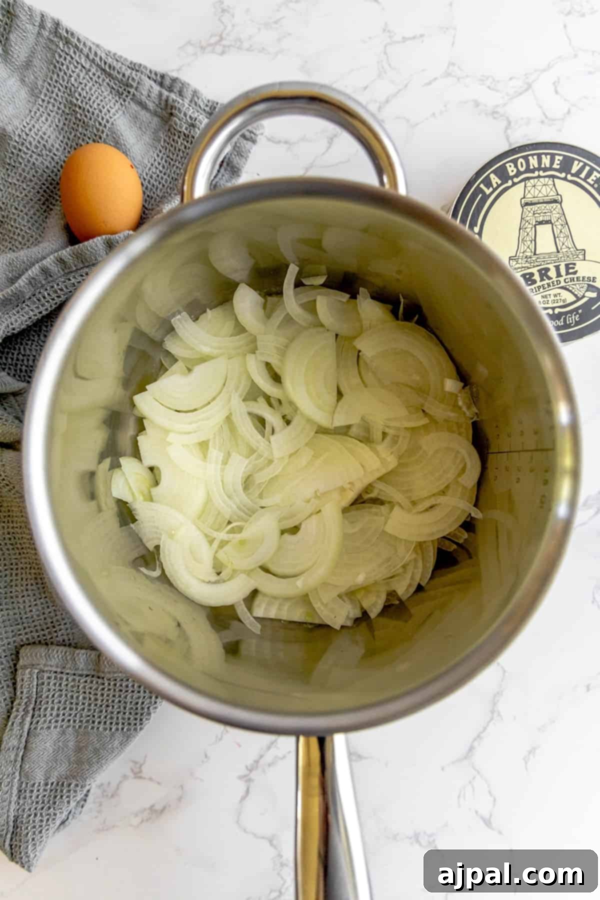 Thinly sliced yellow onions slowly caramelizing in a saucepan with melted butter.
