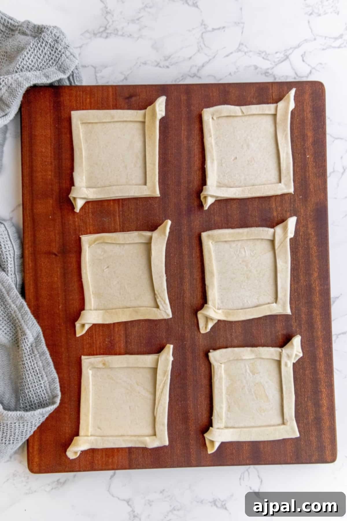 A square-shaped puff pastry with its corners gently folded inwards, ready to hold the filling.