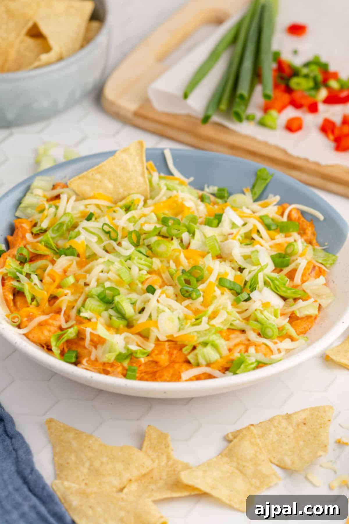 Zesty Taco Dip 3 A vibrant hot taco dip, served in a rustic bowl with plenty of crunchy tortilla chips.
