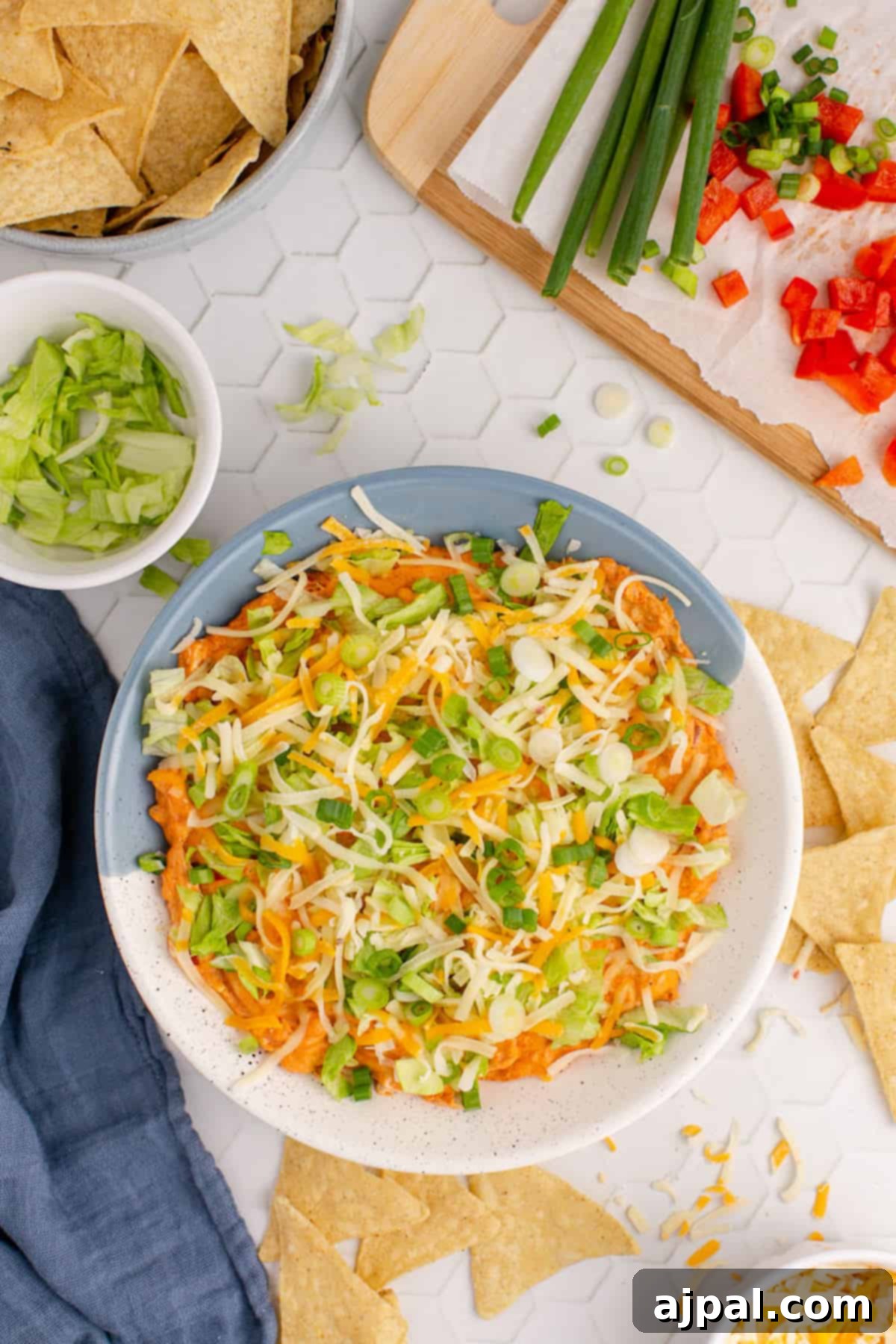 Zesty Taco Dip 10 A hot, cheesy taco dip, garnished beautifully and served with a side of crispy tortilla chips, inviting guests to dig in.
