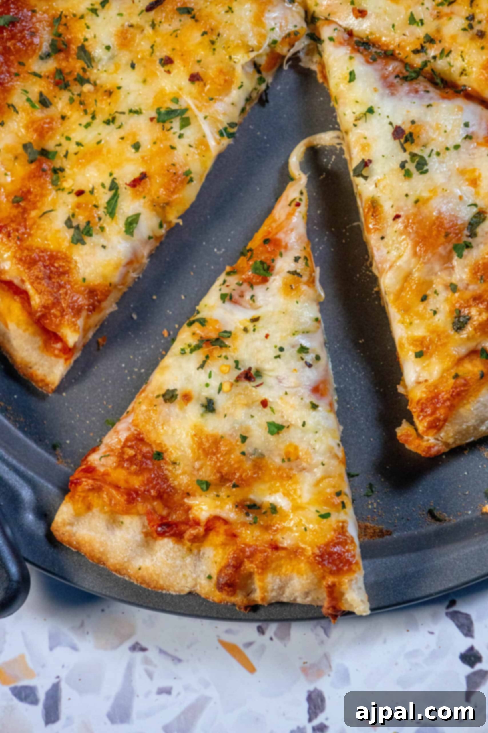 A perfectly baked slice of homemade pizza on a white plate, showcasing its golden, bubbly cheese and crispy crust.