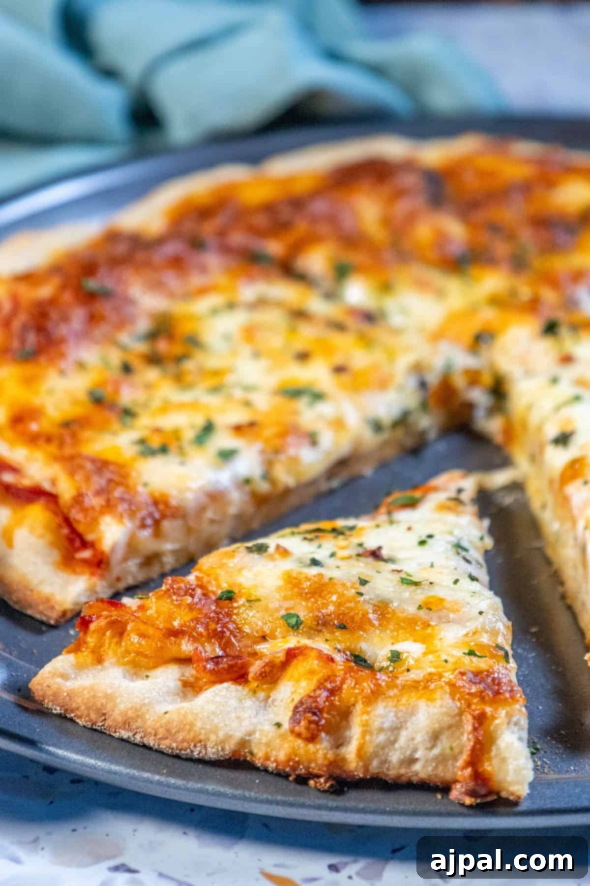 An easy homemade cheese pizza topped with fresh herbs, served on a round plate, ready to be sliced.
